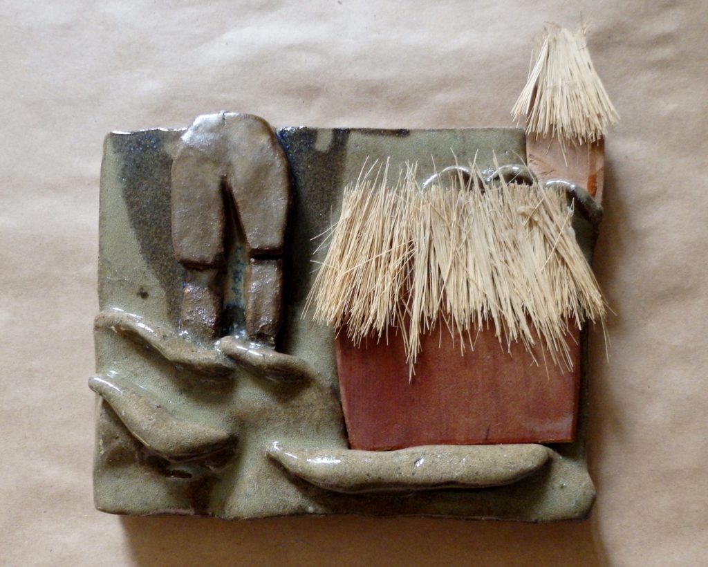 Clay sculpture of man's legs and huts in water